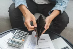 Personne montrant un porte-monnaie vide, symbolisant les difficultés financières, en lien avec l'Aide Sociale Équivalente (ASE) pour les bénéficiaires de soutien financier.